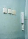 Three white light switches and intercom on an old aqua wall Royalty Free Stock Photo