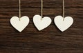 Three White Love Valentine's hearts hanging on wooden texture ba