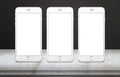 Three white mobile phones on table with blank, white, isolated display screen for mockup Royalty Free Stock Photo