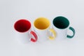 Three white mugs, with a green, yellow, red handl Royalty Free Stock Photo