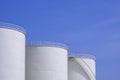 Three white oil storage fuel tanks against blue sky background Royalty Free Stock Photo