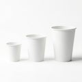 Three white paper cups of varying sizes on a white background Royalty Free Stock Photo
