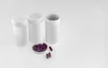 Three white  plastic jars and dark red medicine  capsules on a white background Royalty Free Stock Photo
