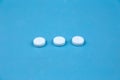 Three white round pills on blue background. Concept of healthcare and medicine communication Royalty Free Stock Photo