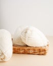 Three white skeins of yarn and a wicker basket. Nice photo for a hobby, vertical orientation. Hobby aesthetics. Royalty Free Stock Photo