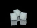 Three white sugar cubes from crystals on black glossy glass Royalty Free Stock Photo