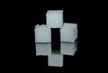 Three white sugar cubes from crystals on black glossy glass Royalty Free Stock Photo