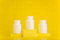 White medication bottles on yellow winner pedestal against yellow background with space for text. Concept of pharmacy