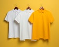 three white and yellow polo shirts hanging on clothes hangers Royalty Free Stock Photo