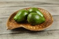 Three whole avocado pears in wooden bowl, on rustic table. Royalty Free Stock Photo