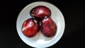 Three whole avocados that are ripe and ready to be enjoyed on a white plate.