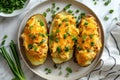 Three whole baked potatoes in jacket stuffed with chicken, green onions and cheddar cheese flat lay on plate on white background Royalty Free Stock Photo