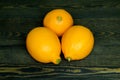 Three whole bright yellow lemons laid out on a coarse wooden authentic background Royalty Free Stock Photo