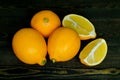 Three whole bright yellow lemons and two halves laid out on a rough wooden authentic background Royalty Free Stock Photo