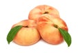 Three whole flat peaches with green leaves (isolated)