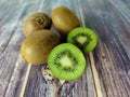 Three whole kiwi fruit and two half. Tropical green fruit on a wooden table. Close up