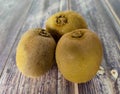 Three whole kiwi. Tropical green fruit on a wooden table. Close up