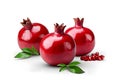 Three whole ripe pomegranates with leaves and seeds on a white background.