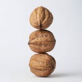 Three whole walnuts stacked vertically against a white background Royalty Free Stock Photo