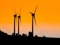 Three wind turbines used for ecological producing electric energy. Sunset silhouettes Royalty Free Stock Photo