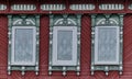 Three windows with carved wooden architraves on facade of Russian house. Royalty Free Stock Photo