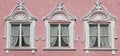 Three windows on pink house wall with stucco ornate Royalty Free Stock Photo