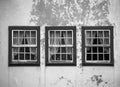 Three windows on the shabby wall closed with curtains