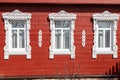 Three windows with white carved platbands on the wall of an old wooden Russian manor house. Royalty Free Stock Photo