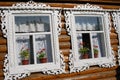 Three windows of a wooden county house decorated by white frames