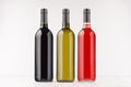 Three wine bottles different colors on white wooden board, mock up.