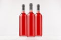 Three wine bottles with rose wine on white wooden board, mock up. Royalty Free Stock Photo