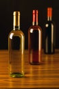 Three wine bottles on wooden table and black background Royalty Free Stock Photo