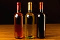 Three wine bottles on wooden table and black background Royalty Free Stock Photo