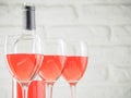 Three wineglass with pink wine and bottle on white brick wall background Royalty Free Stock Photo