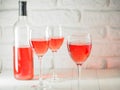 Three wineglass with pink wine and bottle on white brick wall background Royalty Free Stock Photo