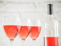 Three wineglass with pink wine and bottle on white brick wall background Royalty Free Stock Photo