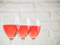 Three wineglass with pink wine on white brick wall background Royalty Free Stock Photo