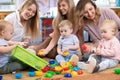 Three woman friends with toddlers playing on the floor in sitting room Royalty Free Stock Photo