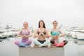 Three woman have meditation on yoga class, outdoor on marine pier. Royalty Free Stock Photo