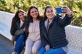 Three woman mother and daughters making selfie by smartphone sitting on bench at park