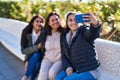 Three woman mother and daughters making selfie by smartphone sitting on bench at park