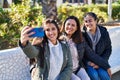 Three woman mother and daughters making selfie by smartphone sitting on bench at park