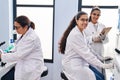 Three woman scientists holding sample write on checklist at laboratory