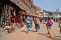 Three women in beautiful bright costumes walking along the historical buildings and the souvenir shops near Boudhanath, Nepal