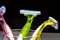 Three women colorful razors with selective focus in a glass beaker on a black background. Royalty Free Stock Photo