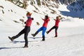 Three women doing a synchronous balance pose on snow, on a sunny Winter day in Bucegi mountains, Romania.