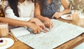 Three women exploring map, deciding where to travel this summer