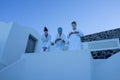 Three women in face masks and robes standing in a white building in Santorini, Greece.