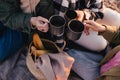 Three women female friends having picnic, drinking hot tea from iron mugs, sitting on beach Royalty Free Stock Photo