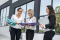 Three women with folders standing outside building and looking in documents Royalty Free Stock Photo